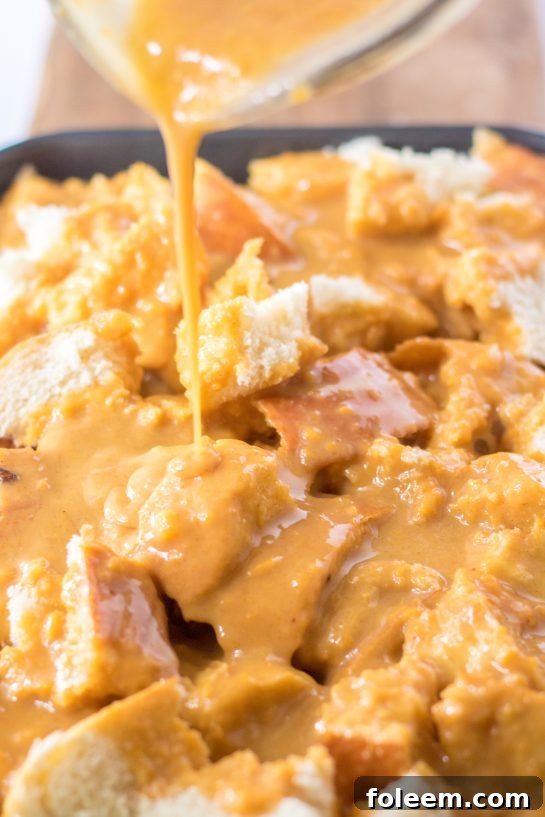 A close-up view of the sweet potato custard mixture, rich in texture and color, as it saturates the bread cubes, promising a moist and flavorful casserole.