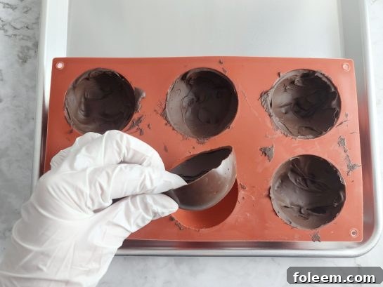 Carefully removing chocolate half-spheres from molds after setting for Hot Chocolate Bombs.