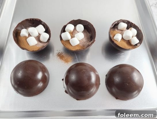 Filling chocolate half-spheres with marshmallows and hot cocoa mix to create Hot Chocolate Bombs.