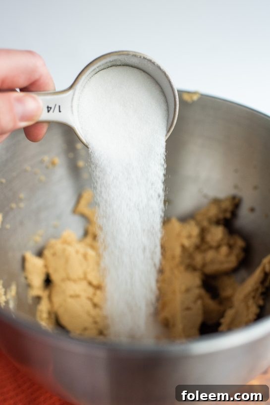 Pouring in the sugar needed for the Peanut Butter Thumbprint Cookies recipe 
