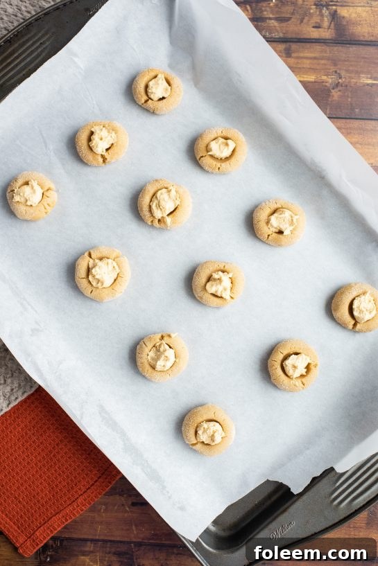 Scooping the filling in for the Peanut Butter Thumbprint Cookies recipe 