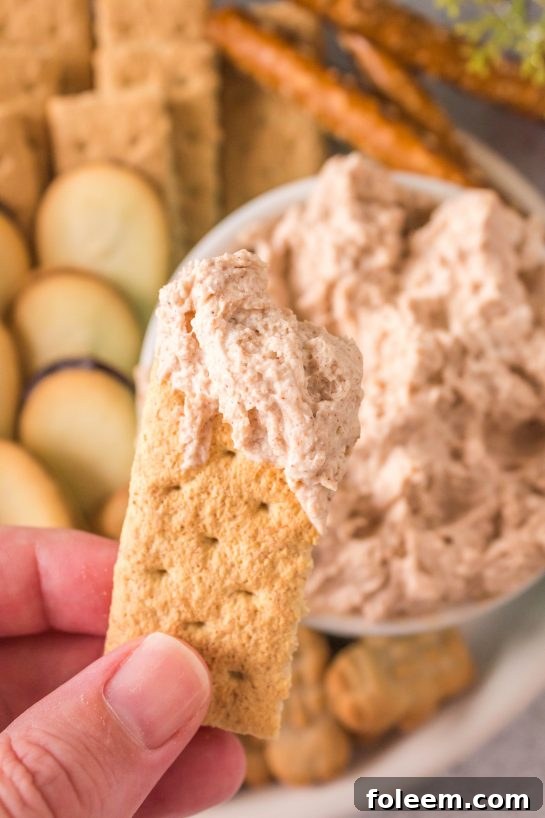 Photo of dipping the graham crackers in the Cinnamon Roll Dip recipe for Christmas