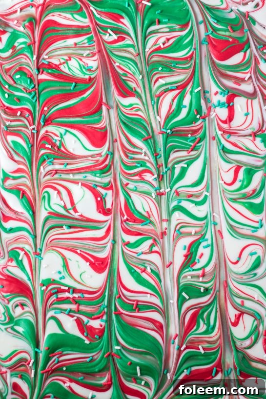 Close-up of a festive Christmas Ritz Cracker Toffee piece with red and green swirls and sprinkles.
