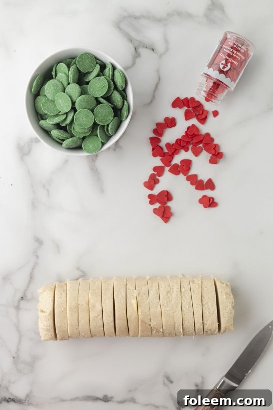 Hands slicing ready-to-bake sugar cookie dough for Grinch Cookie Cup Bites.