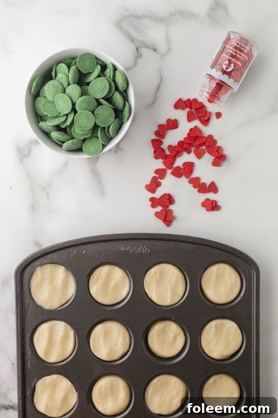 Cookie dough balls being pressed into a mini muffin tin for baking.