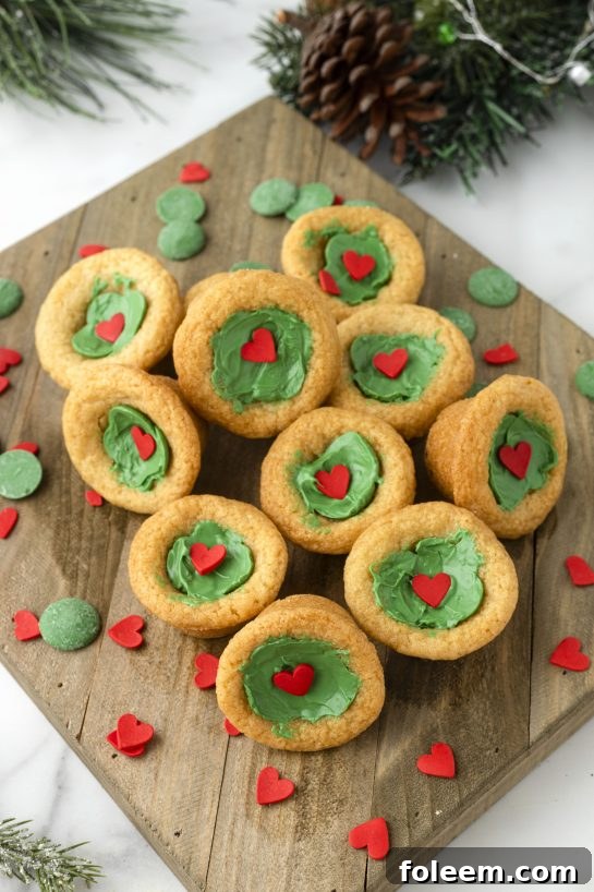 Close-up of baked Grinch Cookie Cup Bites with green centers and red hearts.
