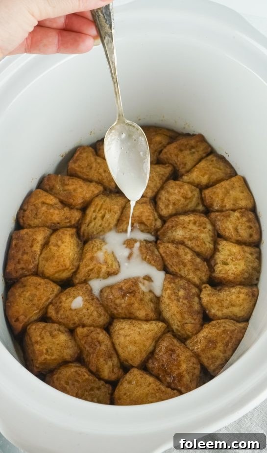 Pouring rich vanilla icing over the warm slow cooker monkey bread.