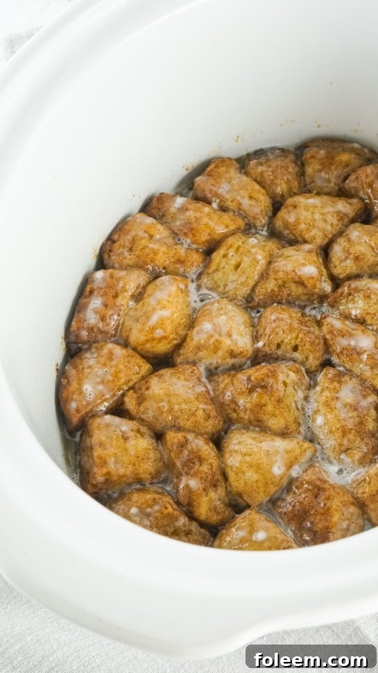 Icing generously covering the pull-apart biscuits in the crock pot.