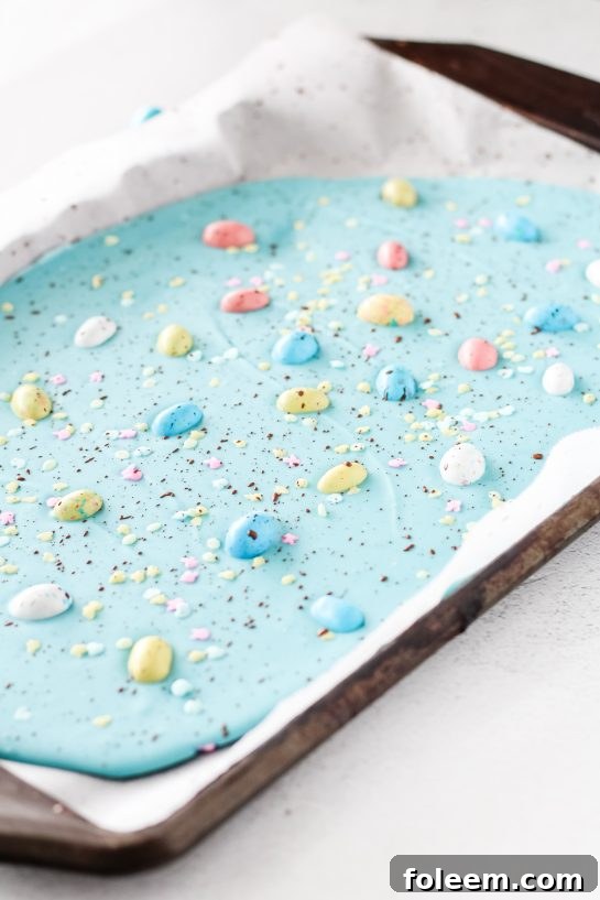 Placing the sprinkles, cocoa powder, and Robin Eggs onto the blue melting chocolate discs for the No-Bake Robin Egg Easter Bark recipe