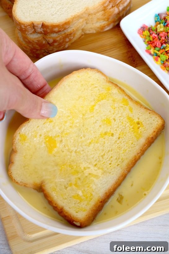 Dipping a slice of thick bread into the prepared egg mixture, ensuring it's fully coated before the cereal step.
