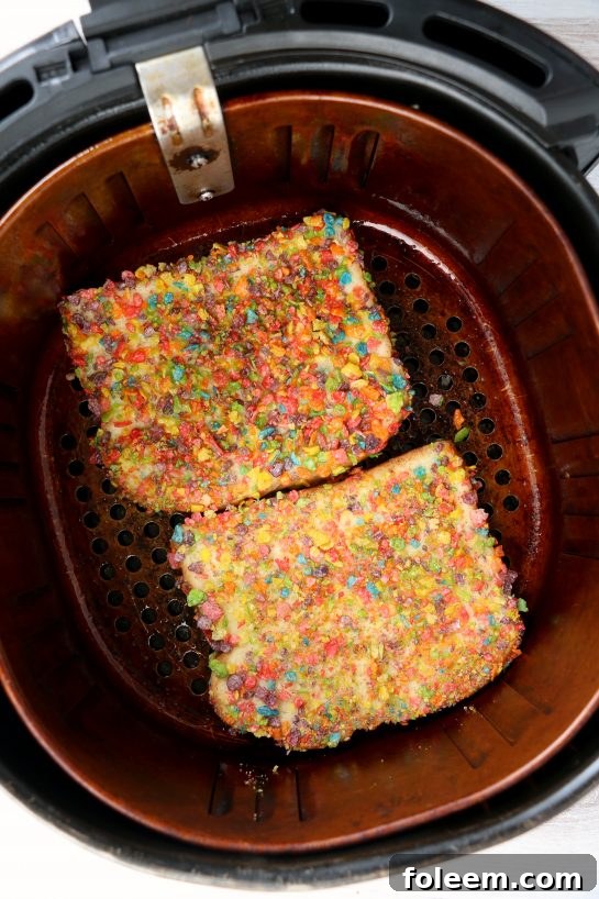 Placing bread slices, coated in egg mixture and Fruity Pebbles, into the air fryer basket for cooking.