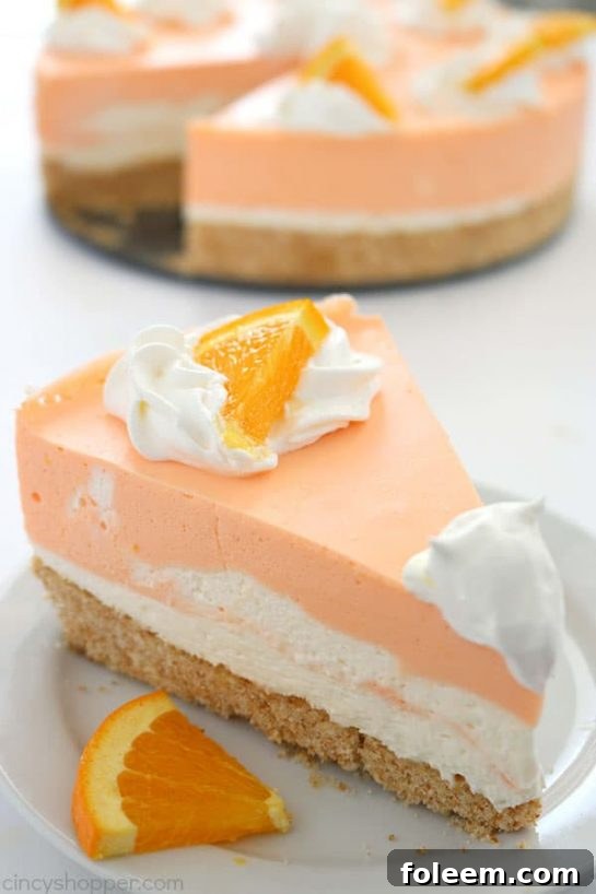 A slice of No Bake Orange Creamsicle Cheesecake with a Nilla Cookie crust and creamy orange cheesecake filling, garnished with orange zest.