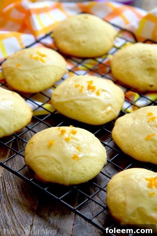 A stack of soft Orange Creamsicle Cookies with a light orange glaze, dusted with powdered sugar.