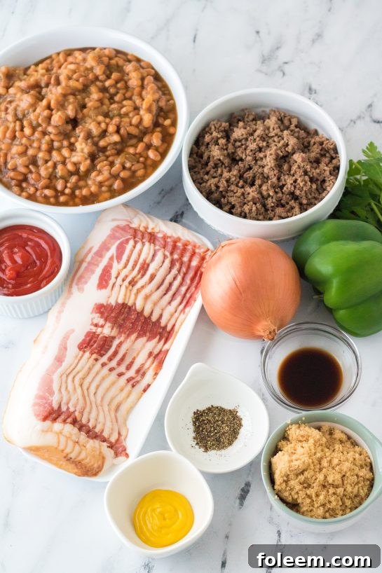 A flat lay photograph showcasing all the fresh and canned ingredients needed for the Beefy Baked Beans recipe, including canned pork & beans, ground beef, diced onion, bell pepper, brown sugar, ketchup, mustard, Worcestershire sauce, and raw bacon.