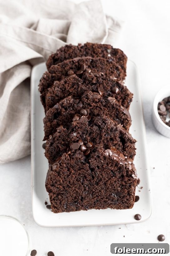 A beautifully baked loaf of chocolate zucchini bread, featuring a rich dark brown crumb and visible chocolate chips, promising a truly decadent experience.