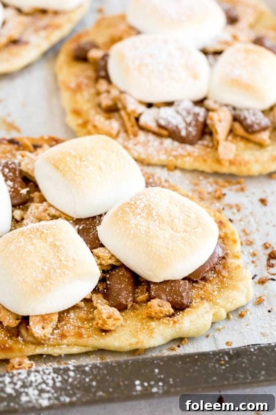 S’mores Flatbread Dessert Pizza: slathered with cinnamon-sugar butter, topped with crumbled graham crackers, ooey gooey chocolate, and marshmallows.