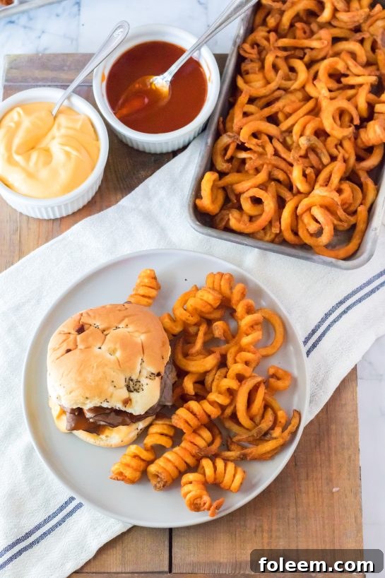 Close-up overhead shot of a delicious copycat Arby's Beef & Cheddar sandwich served with crispy spicy curly fries.