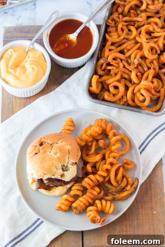 Overhead shot of two homemade Arby's Beef & Cheddar sandwiches, complete with spicy curly fries, ready to be enjoyed.