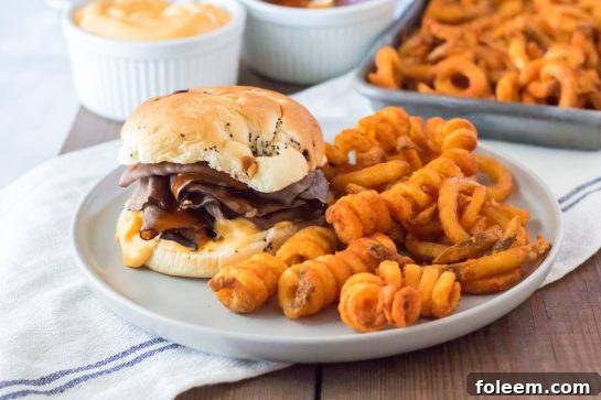A perfectly plated copycat Arby's Beef & Cheddar meal, including a side of delicious spicy curly fries.