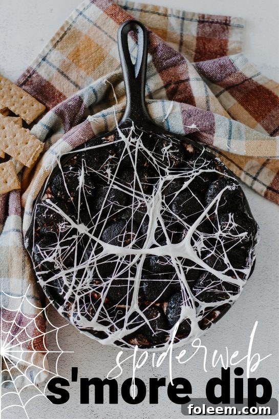 Spiderweb S'mores Dip with gooey marshmallows and melted white chocolate, served with graham crackers for a fun Halloween party