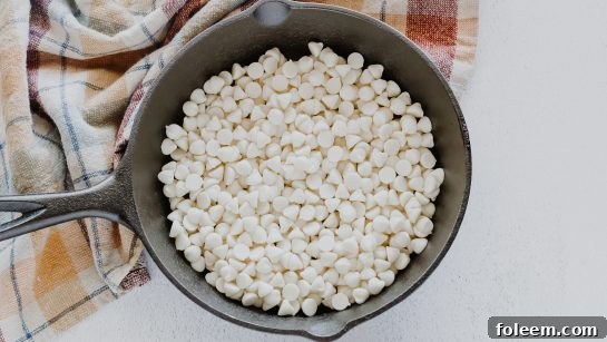 Melting white chocolate chips in an iron skillet, the first step for a delicious and easy S'mores dip