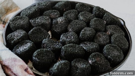 Applying black sugar to marshmallows for the Spiderweb S'mores Dip, creating a spooky Halloween effect