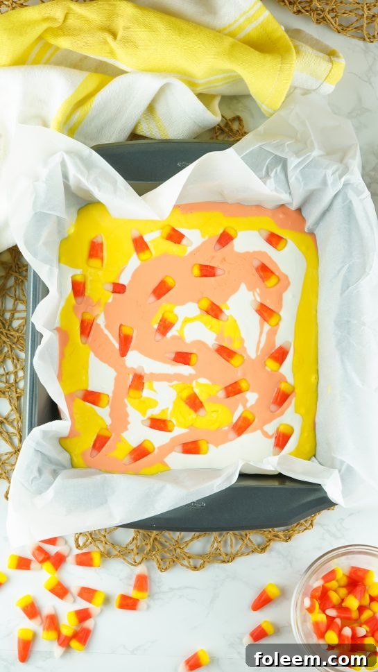 Placing the candy corn on the melted white chocolate needed to make the No-Bake Candy Corn Fudge recipe