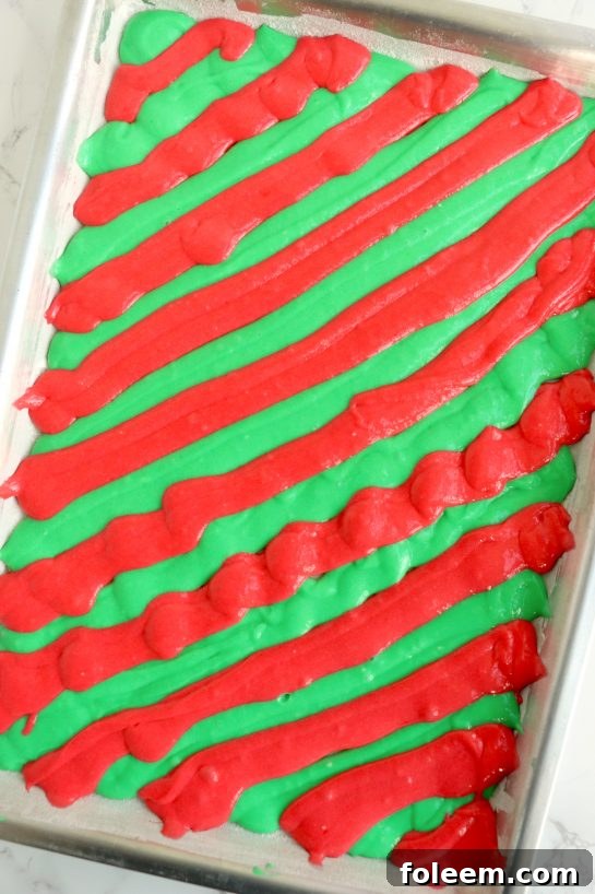 Piping the red and green cake batter in a diagonal pattern into a prepared jelly roll pan to create a beautiful Christmas design.