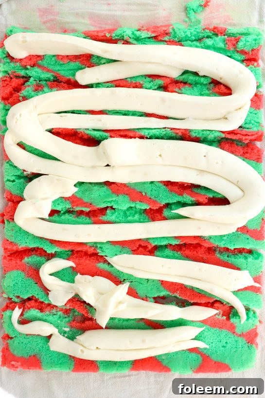 Carefully piping the smooth vanilla whipped frosting onto the baked and unrolled cake, ready for re-rolling into a festive Christmas treat.