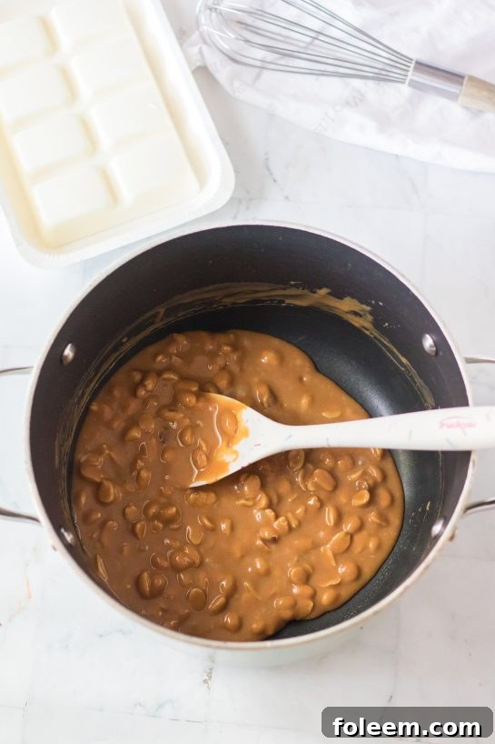 Melted caramel mixed with roasted peanuts, ready to be shaped for the candy clusters.