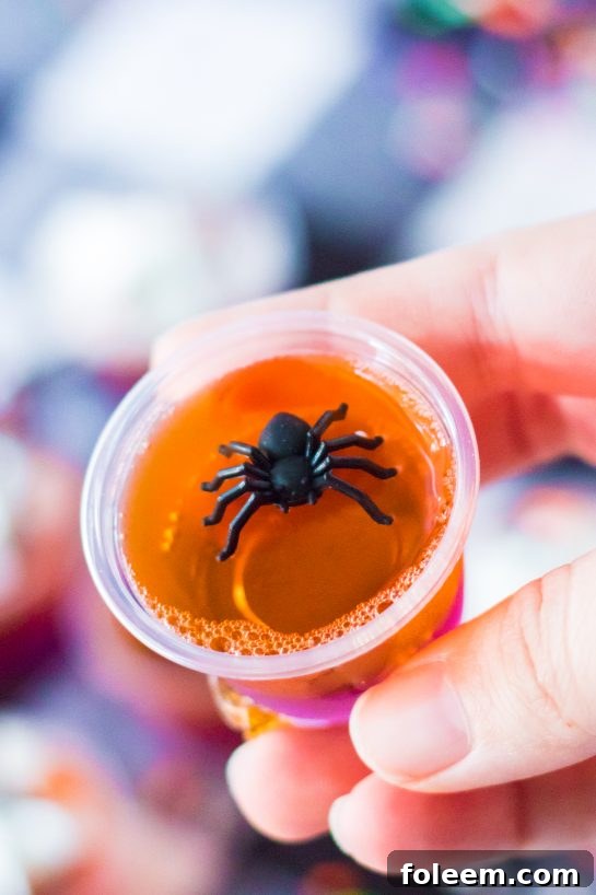 Close-up of finished Halloween Jello Shots adorned with plastic spiders, making them a spooky addition to any Halloween party.