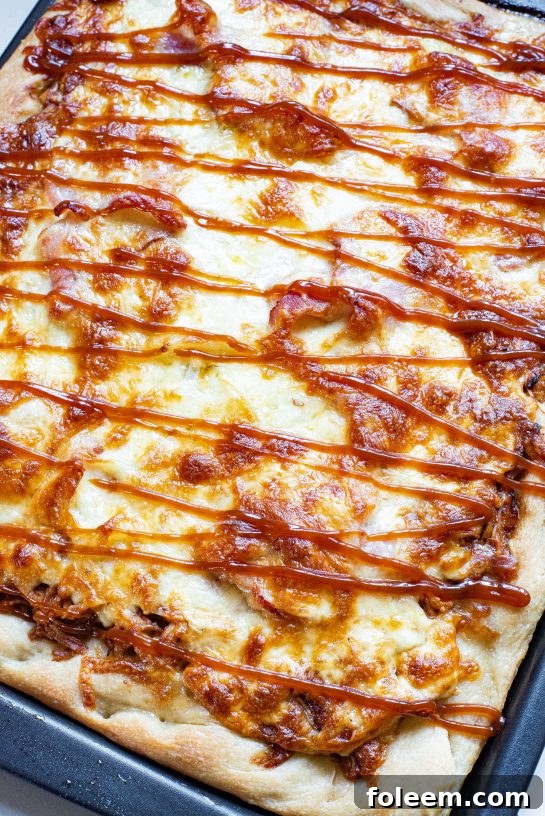 A freshly baked Sheet Pan BBQ Chicken Pizza, hot out of the oven, showcasing its golden crispy crust, melted cheese, and ample toppings.