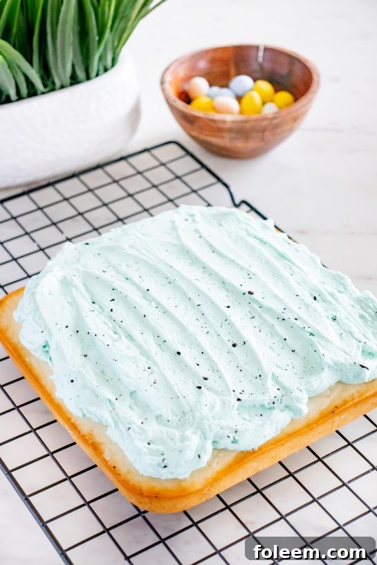 Smoothly frosted Easter Speckled Egg Snack Cake with a light blue buttercream ready for speckles