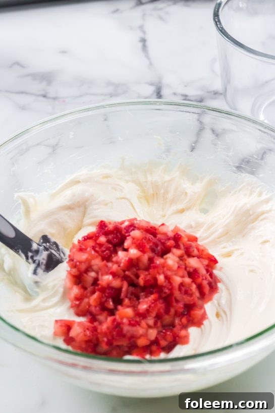 Mixing in the chopped strawberries needed to make the Strawberries & Cream Layered Cake recipe