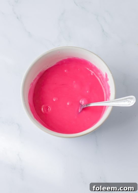 Mixing powdered sugar and water with a touch of pink food coloring to create the vibrant strawberry icing.
