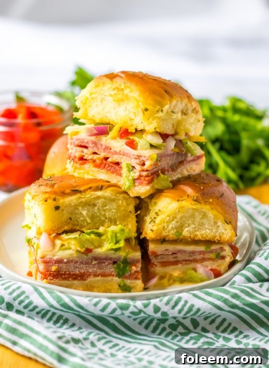 Italian Sub Sliders with ham, salami, pepperoni, and provolone, baked until melty and topped with fresh veggies.