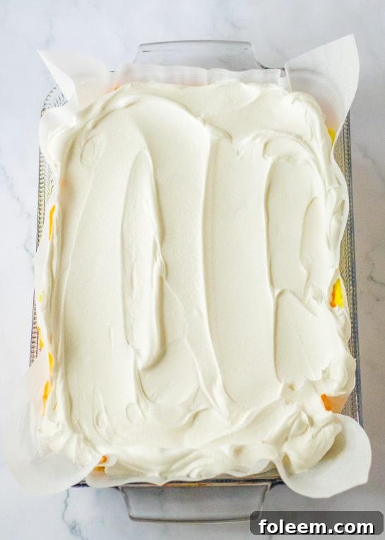 Spreading on the whipped topping needed to make the candy corn lush for fall dessert recipe