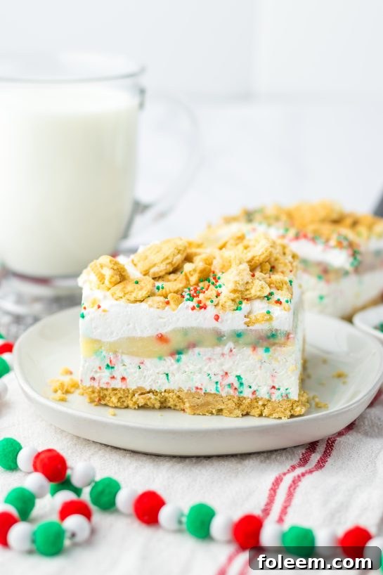 Christmas Cookie Lush, a festive no-bake holiday dessert featuring layers of vanilla cream cookies, creamy cheesecake, smooth pudding, whipped topping, and joyful sprinkles.