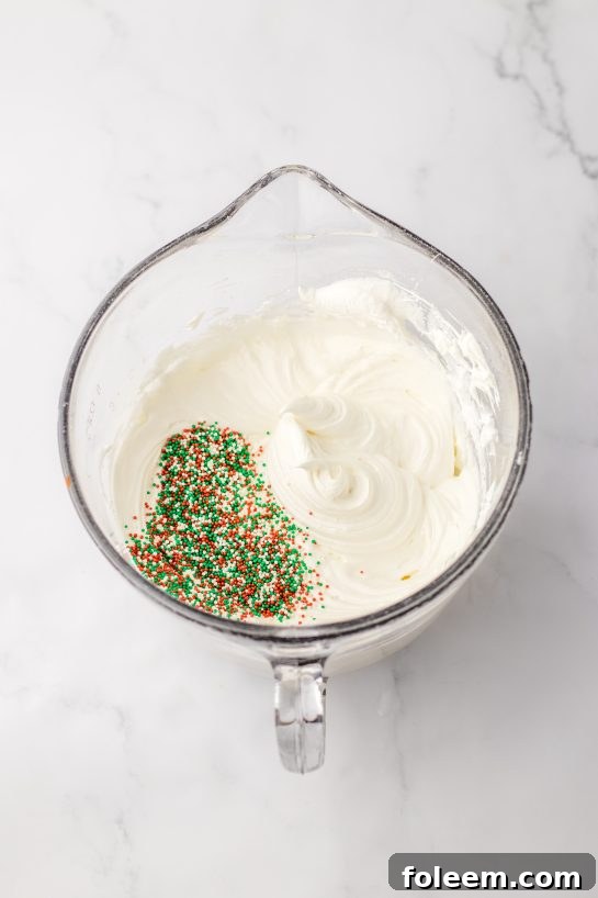 Mixing the creamy cheesecake layer with colorful holiday sprinkles for the Christmas Cookie Lush recipe.