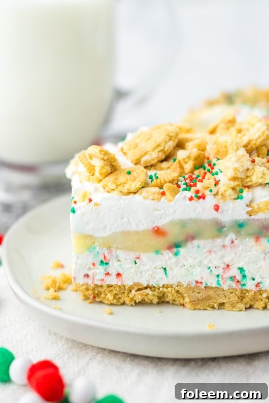 Close-up of a festive Christmas Cookie Lush dessert, showcasing its beautiful layers of vanilla cookies, cheesecake, pudding, whipped topping, and sprinkles.