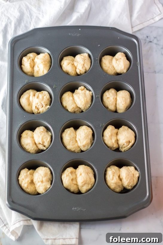 Unbaked Mashed Potato Rolls neatly arranged in a muffin tin, ready to be placed in the oven for a delicious holiday meal.