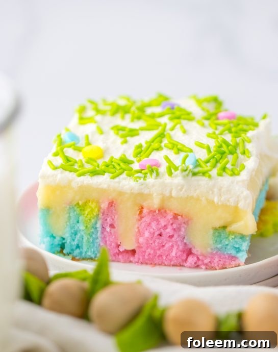 A beautifully layered Easter Poke Cake with pastel colors, white chocolate pudding, and whipped cream topping, ready for spring celebrations.