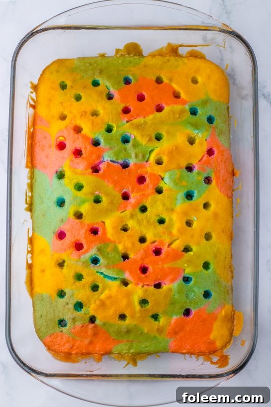 Poking holes into the freshly baked, colored cake with a wooden spoon for the Easter Poke Cake recipe.