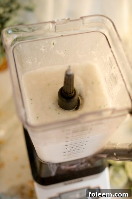 Capturing the moment of blending all ingredients for the Coconut Lime Frozen Margaritas recipe in a high-powered blender, creating a perfectly smooth and frosty consistency.