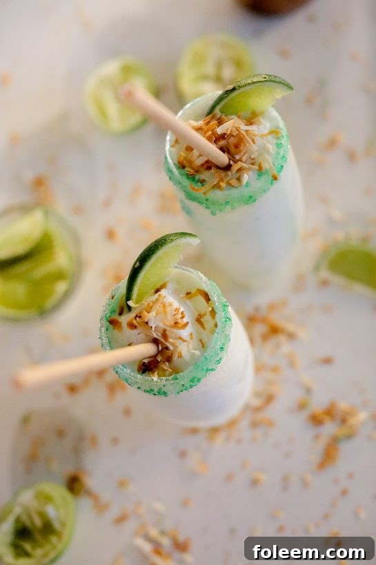 Coconut Lime Frozen Margaritas: a smooth, creamy, and easy-to-make frozen drink recipe, perfect for leisurely sipping at any vibrant summer party. This delightful concoction features a harmonious blend of creamy coconut, premium tequila, and zesty fresh lime, all elegantly finished with a delightfully crunchy toasted coconut rim.