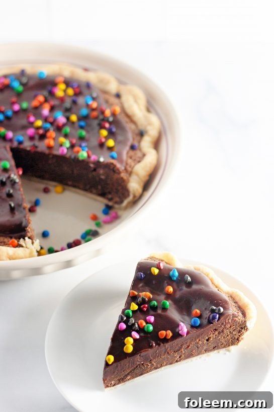 A delectable slice of Cosmic Brownie Pie sits plated, with the remaining whole pie visible in the background.