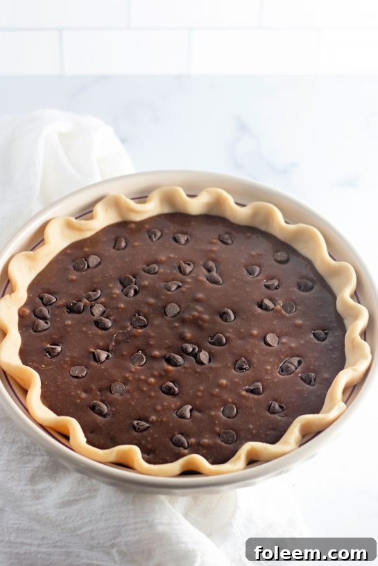 Cosmic Brownie Pie batter beautifully spread within a pie crust, poised for baking in the oven.