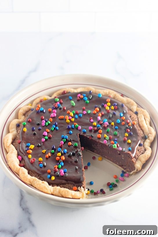 A slice of Cosmic Brownie Pie has been carefully removed from the full pie, showing its delicious layers.
