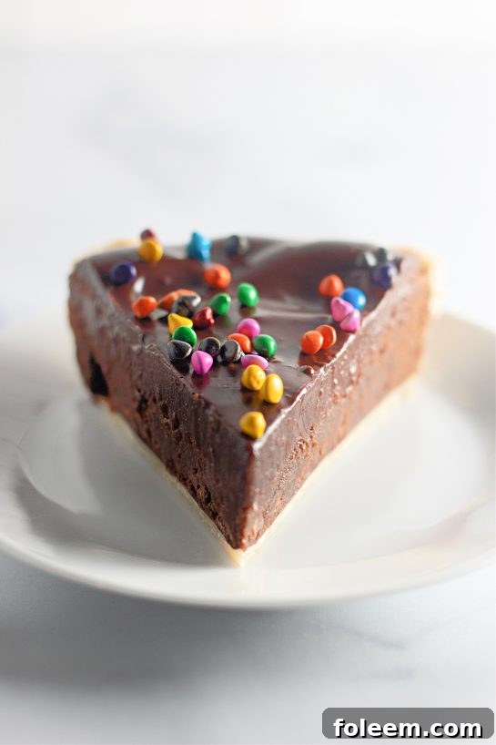 A perfectly plated slice of Cosmic Brownie Pie, showcasing its rich fudgy texture, flaky crust, and vibrant sprinkles.