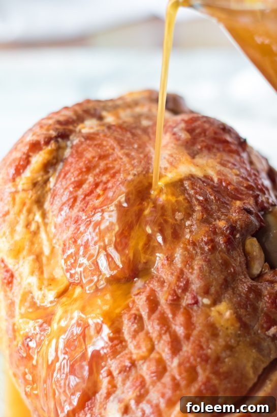 Detailed close-up shot of the rich, viscous glaze being poured over the intricate cuts of a spiral-sliced ham.